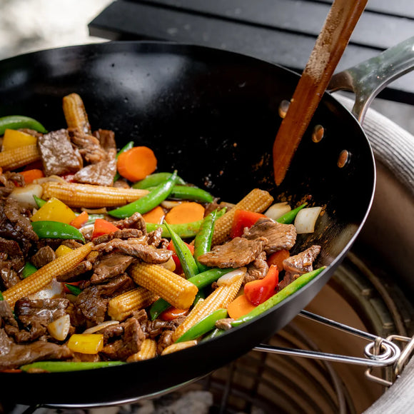 Wok with stir-fried vegetables and meat on a stove