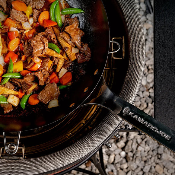 Stir-fry with vegetables and meat in a wok on a grill
