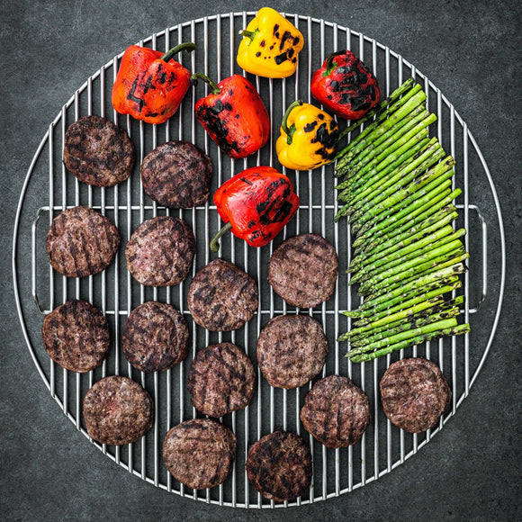 Grill with hamburgers, bell peppers, and asparagus on a dark background