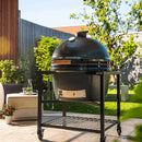 Large ceramic barbecue grill on a stand in an outdoor garden setting
