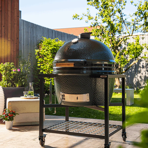 Large ceramic barbecue grill on a stand in an outdoor garden setting